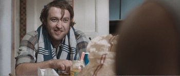 Movie still from “The Misfortunates” (2009), directed by Felix van Groeningen – A man sitting at a table with a bottle of juice; Close Up shot, Over the shoulder angle