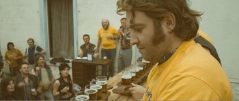 Movie still from “The Misfortunates” (2009), directed by Felix van Groeningen – A group of people standing around a table with beer; Close Up shot, Over the shoulder angle