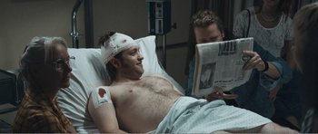 Movie still from “The Misfortunates” (2009), directed by Felix van Groeningen – A man in a hospital bed reading a newspaper; Medium shot, Over the shoulder angle