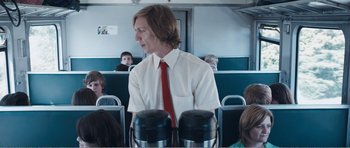 Movie still from “The Misfortunates” (2009), directed by Felix van Groeningen – A man standing on a train with a bunch of people behind him; Medium shot, Over the shoulder angle