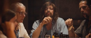 Movie still from “The Misfortunates” (2009), directed by Felix van Groeningen – A man sitting at a table with a cigarette in his mouth; Medium shot, Over the shoulder angle