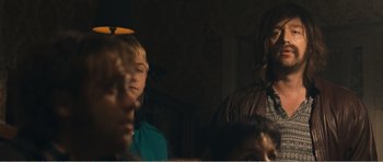 Movie still from “The Misfortunates” (2009), directed by Felix van Groeningen – A group of people sitting in a dark room; Medium shot, Over the shoulder angle