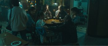 Movie still from “The Misfortunates” (2009), directed by Felix van Groeningen – A group of people sitting around a table in a room; Wide shot, High angle