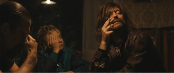 Movie still from “The Misfortunates” (2009), directed by Felix van Groeningen – A man smoking a cigarette while another man watches; Medium shot, Over the shoulder angle