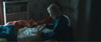 Movie still from “The Misfortunates” (2009), directed by Felix van Groeningen – A woman sitting in a chair playing a keyboard; Medium shot, High angle