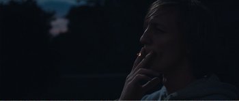 Movie still from “The Misfortunates” (2009), directed by Felix van Groeningen – A person smoking a cigarette in the dark; Close Up shot, Over the shoulder angle