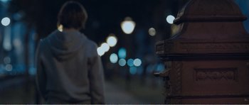 Movie still from “The Misfortunates” (2009), directed by Felix van Groeningen – A person standing next to a fire hydrant at night; Medium shot, Over the shoulder angle