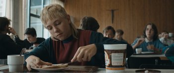 Movie still from “The Misfortunates” (2009), directed by Felix van Groeningen – A woman is eating food at a table with other people; Medium shot, Over the shoulder angle