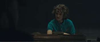 Movie still from “The Misfortunates” (2009), directed by Felix van Groeningen – A person sitting in front of a table; Medium shot, Over the shoulder angle