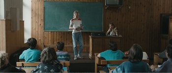 Movie still from “The Misfortunates” (2009), directed by Felix van Groeningen – A woman standing in front of an audience in front of a chalkboard; Wide shot, Over the shoulder angle