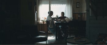 Movie still from “The Misfortunates” (2009), directed by Felix van Groeningen – Two people sitting at a table in a room; Wide shot, Over the shoulder angle