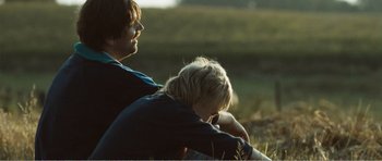 Movie still from “The Misfortunates” (2009), directed by Felix van Groeningen – A man and a boy sitting in the grass; Close Up shot, Over the shoulder angle