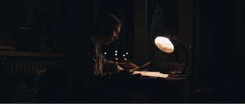 Movie still from “The Misfortunates” (2009), directed by Felix van Groeningen – A man sitting at a table using a laptop computer at night; Medium shot, Low angle