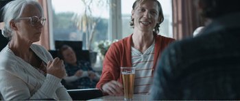 Movie still from “The Misfortunates” (2009), directed by Felix van Groeningen – A woman sitting at a table with a glass of beer; Medium shot, Over the shoulder angle