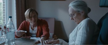 Movie still from “The Misfortunates” (2009), directed by Felix van Groeningen – Two women sitting at a table looking at a book; Medium shot, Over the shoulder angle