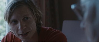 Movie still from “The Misfortunates” (2009), directed by Felix van Groeningen – A person sitting in a room with a red shirt on; Close Up shot, Over the shoulder angle