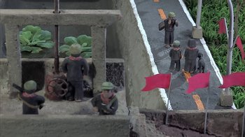 Movie still from “The Missing Picture” (2013), directed by Rithy Panh – A group of men standing next to each other on a street; Extreme Close Up shot, High angle