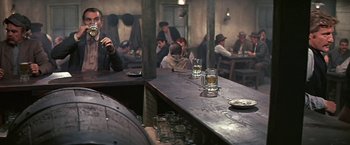 Movie still from “The Molly Maguires” (1970), directed by Martin Ritt – A group of people sitting at a table in a room; Wide shot, Over the shoulder angle