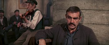 Movie still from “The Molly Maguires” (1970), directed by Martin Ritt – A man sitting in front of a brick wall; Medium shot, Over the shoulder angle