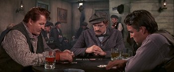 Movie still from “The Molly Maguires” (1970), directed by Martin Ritt – A man sitting at a table playing cards with other men; Medium shot, High angle