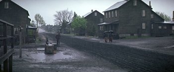 Movie still from “The Molly Maguires” (1970), directed by Martin Ritt – People walking down a street in the pouring rain; Extreme Wide shot, High angle