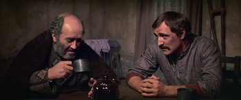 Movie still from “The Molly Maguires” (1970), directed by Martin Ritt – Two men sitting at a table with a drink in front of them; Medium shot, Over the shoulder angle