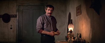 Movie still from “The Molly Maguires” (1970), directed by Martin Ritt – A man standing in front of an oil lamp; Medium shot, Over the shoulder angle
