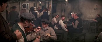Movie still from “The Molly Maguires” (1970), directed by Martin Ritt – A group of men sitting at a table drinking beer; Wide shot, High angle