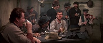 Movie still from “The Molly Maguires” (1970), directed by Martin Ritt – A group of men sitting at a table with drinks; Medium shot, Over the shoulder angle