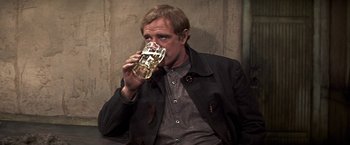 Movie still from “The Molly Maguires” (1970), directed by Martin Ritt – A man drinking a glass of beer while sitting at a table; Close Up shot, Over the shoulder angle