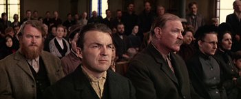 Movie still from “The Molly Maguires” (1970), directed by Martin Ritt – A man in a suit sitting in front of an audience; Medium shot, Low angle