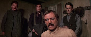 Movie still from “The Molly Maguires” (1970), directed by Martin Ritt – A man with a mustache standing next to another man in a room; Close Up shot, Low angle