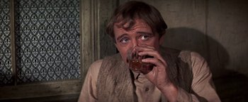 Movie still from “The Molly Maguires” (1970), directed by Martin Ritt – A man drinking from a glass in a room; Close Up shot, Over the shoulder angle