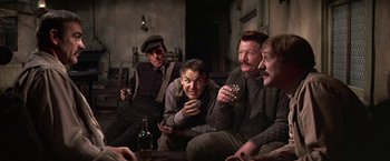 Movie still from “The Molly Maguires” (1970), directed by Martin Ritt – A group of men sitting on a couch drinking beer; Medium shot, Low angle