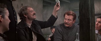 Movie still from “The Molly Maguires” (1970), directed by Martin Ritt – A man holding up a dollar bill to another man's face; Medium shot, Over the shoulder angle