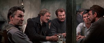 Movie still from “The Molly Maguires” (1970), directed by Martin Ritt – A couple of men sitting at a table with drinks; Medium shot, Over the shoulder angle