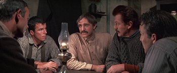 Movie still from “The Molly Maguires” (1970), directed by Martin Ritt – A group of men sitting around a table with an oil lamp; Medium shot, Over the shoulder angle