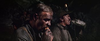 Movie still from “The Molly Maguires” (1970), directed by Martin Ritt – Two men are eating some food in a cave; Close Up shot, High angle