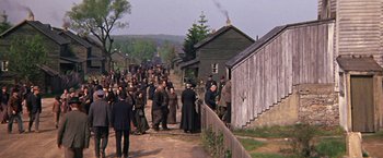 Movie still from “The Molly Maguires” (1970), directed by Martin Ritt – A crowd of people walking down a dirt road; Extreme Wide shot, High angle