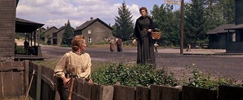 Movie still from “The Molly Maguires” (1970), directed by Martin Ritt – A woman in a long black dress holding a wicker basket; Wide shot, Over the shoulder angle