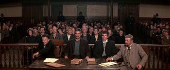 Movie still from “The Molly Maguires” (1970), directed by Martin Ritt – A group of men sitting at a table in front of a crowd; Wide shot, High angle