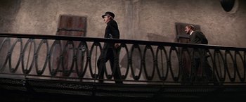 Movie still from “The Molly Maguires” (1970), directed by Martin Ritt – An old man in a hat is walking across a bridge; Wide shot, Low angle