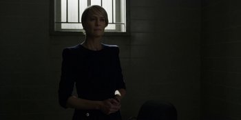 Movie still from “House of Cards” (2013), created by Beau Willimon – A woman standing in a dark room holding a remote control; Medium shot, Low angle