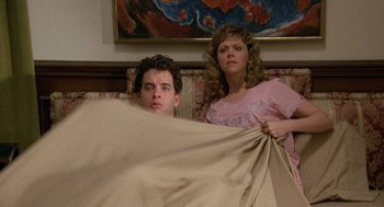 Movie still from “The Money Pit” (1986), directed by Richard Benjamin – A man and a woman are hiding behind a blanket; Medium shot, Low angle
