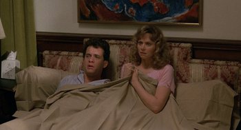 Movie still from “The Money Pit” (1986), directed by Richard Benjamin – A man and a woman sitting on a couch under a blanket; Medium shot, High angle