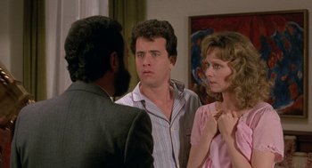 Movie still from “The Money Pit” (1986), directed by Richard Benjamin – Two men and a woman are talking to each other in a living room; Medium shot, Over the shoulder angle
