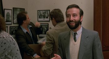 Movie still from “The Money Pit” (1986), directed by Richard Benjamin – A man in a suit and tie in front of two other men; Medium shot, Over the shoulder angle