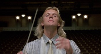 Movie still from “The Money Pit” (1986), directed by Richard Benjamin – A man with long blonde hair wearing a tie; Close Up shot, Low angle