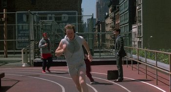 Movie still from “The Money Pit” (1986), directed by Richard Benjamin – A man running on a track while wearing headphones; Wide shot, High angle
