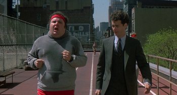 Movie still from “The Money Pit” (1986), directed by Richard Benjamin – Two men walking down a street in a city; Medium shot, Over the shoulder angle